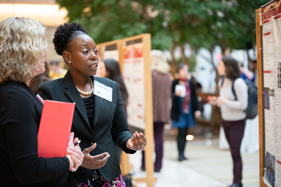 two female scientists talking and looking at a scientific poster during a conference