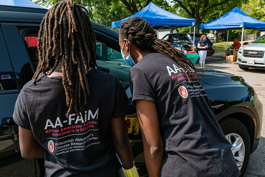 two woman speaking to a person through an open car window at an outdoor event
